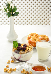 Delicious and healthy breakfast of granola, buns brioche, honey and milk on a light background. Soft focus.