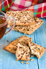 crispy bread with seeds of sunflower, flax and sesame seeds with a cup of tea on a blue wooden background