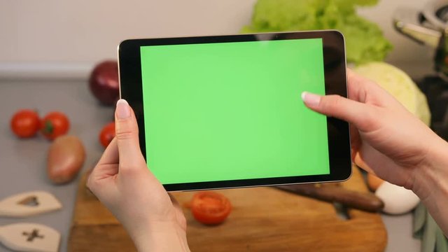 Woman shoot her tablet in the kitchen. Vegetables are on the background.