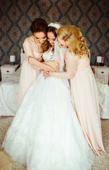 Fototapeta na wymiar Tender hugs of curly bride and gorgeous bridesmaids