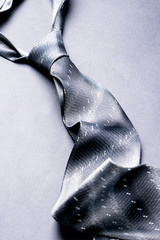 Gray spotted man's knotted tie over gray background