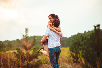 Man and woman in jeans stand hugging on evening field