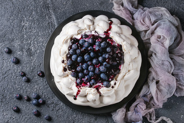 Homemade meringue cake Pavlova with whipped cream, fresh blueberries and blueberry sauce on vintage...