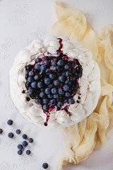 Naklejki  Domowe ciasto bezowe Pavlova z bitą śmietaną, świeżymi jagodami i sosem jagodowym na vintage tort stoją na białym tle tekstury betonu, gaza tekstylna.
