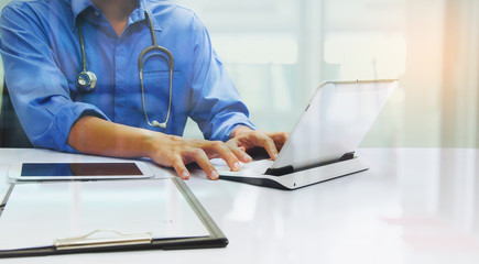 medicine doctor working with computer notebook and digital tablet  at desk in the hospital