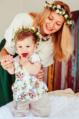 Stunning woman with golden hair holds her little daughter standing on soft bed