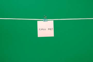 Pink paper note on the string with text Call Me!