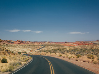 Fototapeta na wymiar A windy empty road going through the hot summer desert of las vegas, nevada