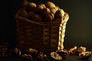 Pełen koszyk orzechów włoskich, na czarnym tle.