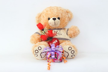 Brown teddy bear with a red rose and a gift box on a white background.