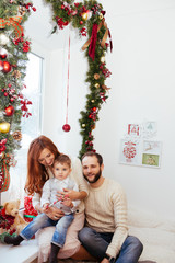 Happy family poses before window decorated with Christmas accessories