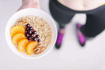 Oatmeal with fruit berries and cereals in the hands of a sportswoman