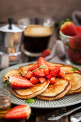 Homemade delicious pancakes served with fresh strawberries and honey