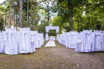 white wedding table set up in forest in summer, the ceremony is outdoor with chairs