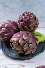 Obraz premium Fresh big Romanesco artichokes green-purple flower heads ready to cook