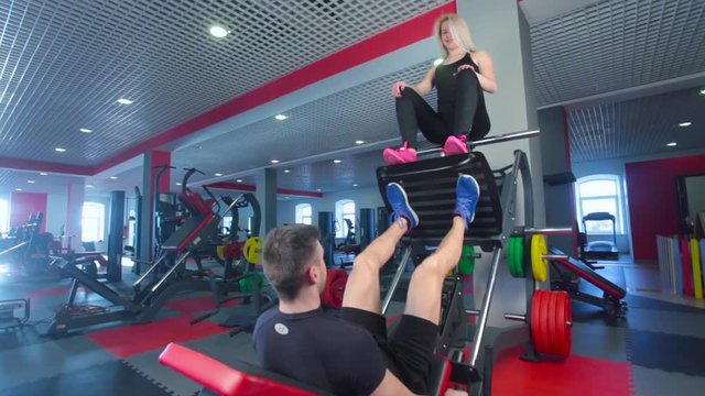 man focused on training legs on the machine in the gym with trainer