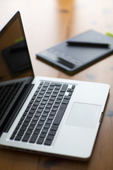 Laptop and graphic tablet on wood table.