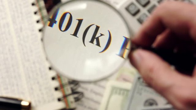 401k plan is watched with magnifier. Retirement concept. Selective focus.