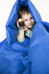 Boy with a toy dog peeking out of a huge blue hood