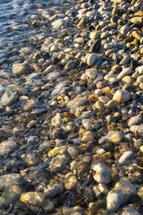 sea pebble beach with multicoloured stones, waves with foam