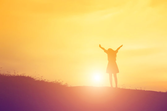 Silhouette of woman praying over beautiful sky background