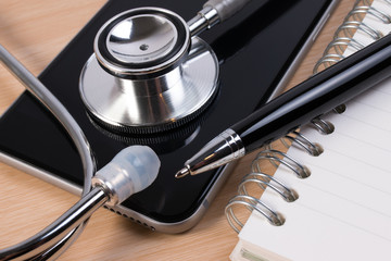 Stethoscope and pen on smartphone checking healthcare security. Stethoscope on smartphone checking security on smartphone. Doctor contact or appointment concept.