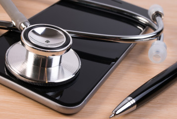Stethoscope and pen on smartphone checking healthcare security. Stethoscope on smartphone checking security on smartphone. Doctor contact or appointment concept.