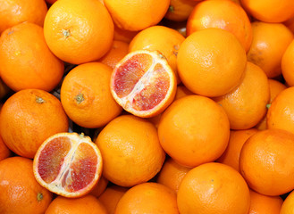 Ripe oranges and an orange cut in the stall of greengrocer