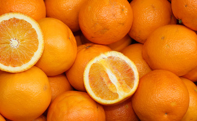 Ripe oranges and an orange cut in the stall of greengrocer