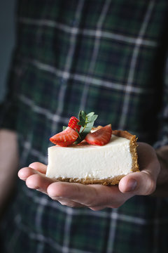 Slice of cheesecake with strawberries on a hand