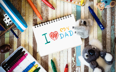 Fathers day greeting card concepts with I love you Dad text and cute dolls. Top view on wooden...