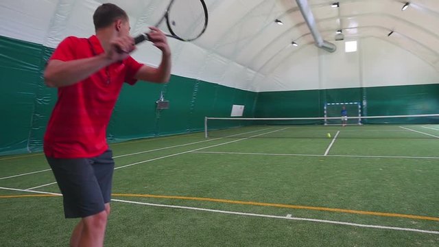A man playing on a grass court tennis in slowmotion