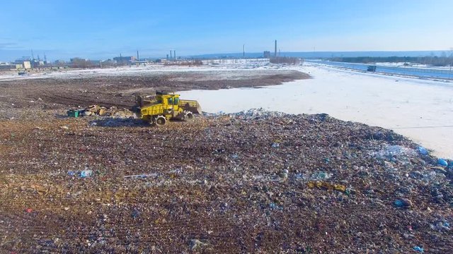 Aerial: tractor working at the garbage dump. Landfill, garbage dump, trash dump from above. 4K.