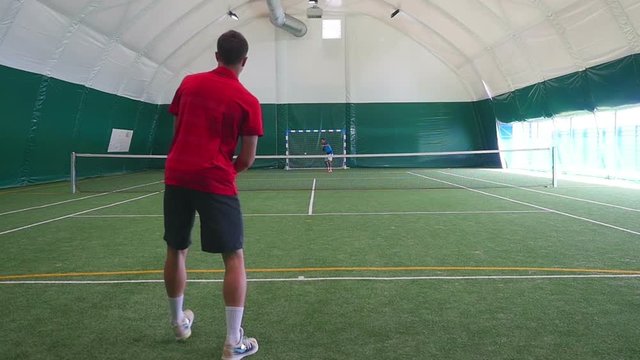 The man pitches a ball with tennis racket on court