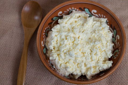 fresh cottage cheese in a plate with a wooden spoon 