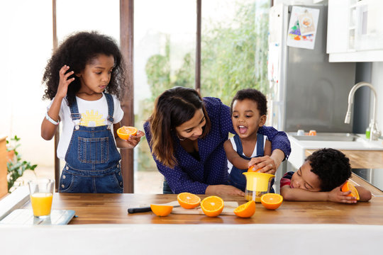 Famille qui pr&eacute;pare du jus d'orange dans la cuisine