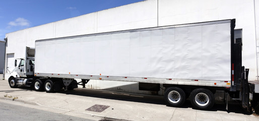 Fototapeta na wymiar Side view of white semi truck trailer and cab.