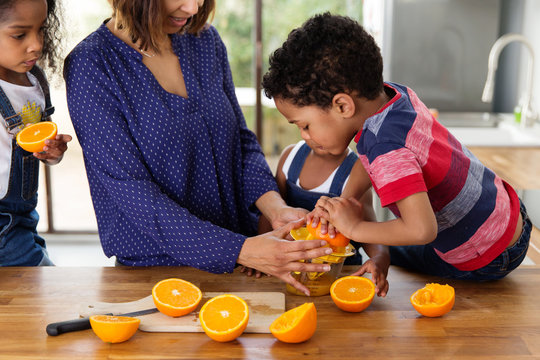 Maman qui aide son petit gar&ccedil;on &agrave; presser des oranges