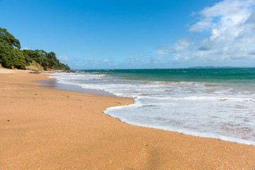 Red sand and blue sea of Cable Bay Northland New Zealand.