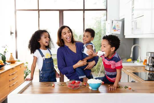 Famille dans la cuisine qui regarde un petit gar&ccedil;on manger de la chantilly &agrave; la cuill&egrave;re