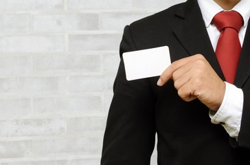businessman showing business card on brick wall background, selective focus, copy space, color tone effect.