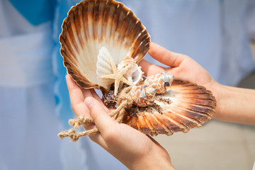 Two wedding rings on handmade ring pillow from seashells on wedding ceremony near sea outdoor. Kid...