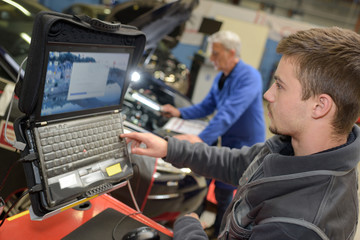 auto mechanic teacher and trainee performing tests at mechanic school