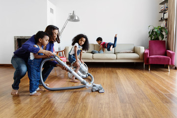 Une maman apprend &agrave; son petit gar&ccedil;on &agrave; passer l'aspirateur