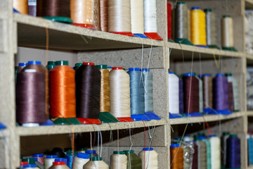 Spools of thread which are on the shelves and the loom