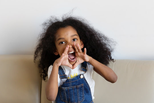 Une petite fille crie en mettant ses mains autour de sa bouche