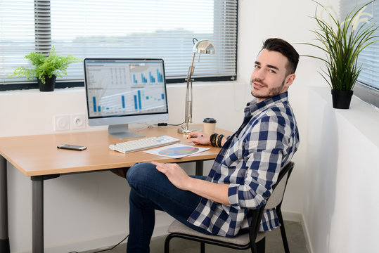 portrait of a young man in casual wear working in creative business startup company office with computer