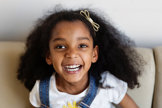 Portrait d'une petite fille qui rit sur le canap&eacute;