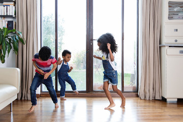 Trois enfants qui dansent devant la fenêtre du salon