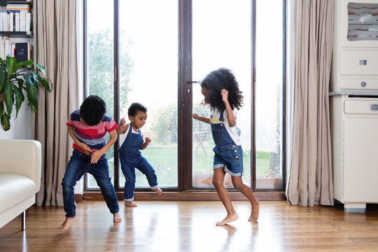 Trois enfants qui dansent devant la fen&ecirc;tre du salon